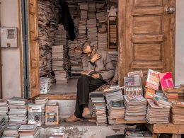 Man reading while surrounded by hundreds of books