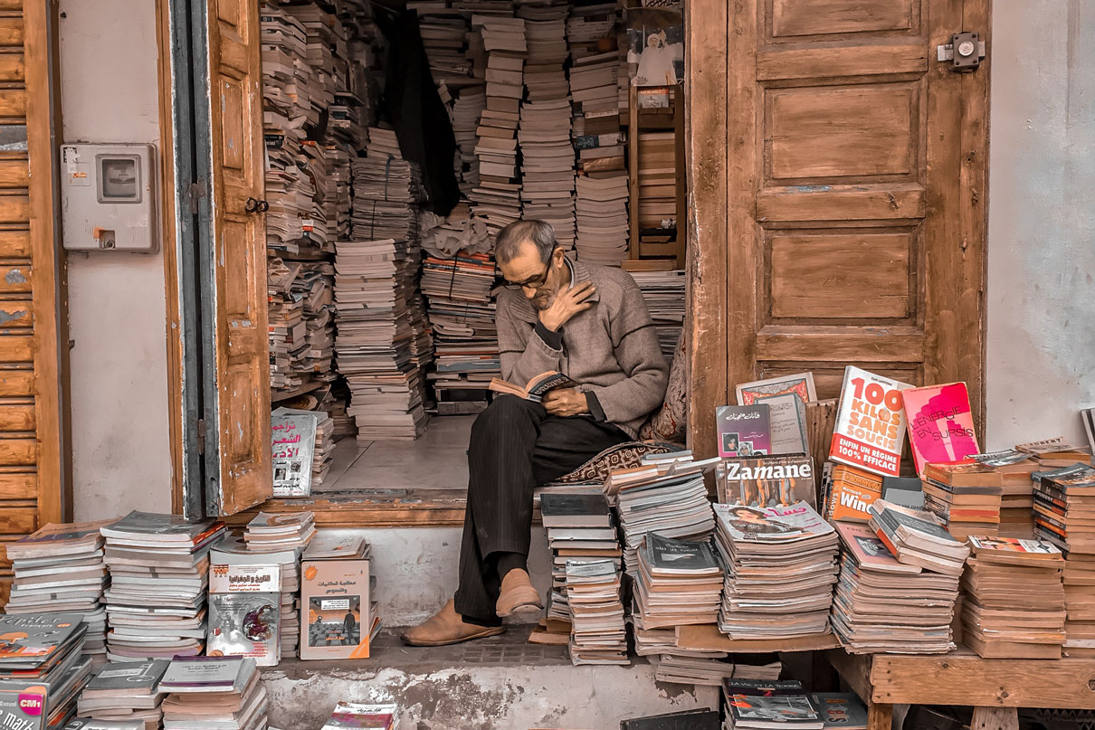 Man reading while surrounded by hundreds of books