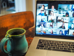Photo of coffee cup beside laptop with video call participants